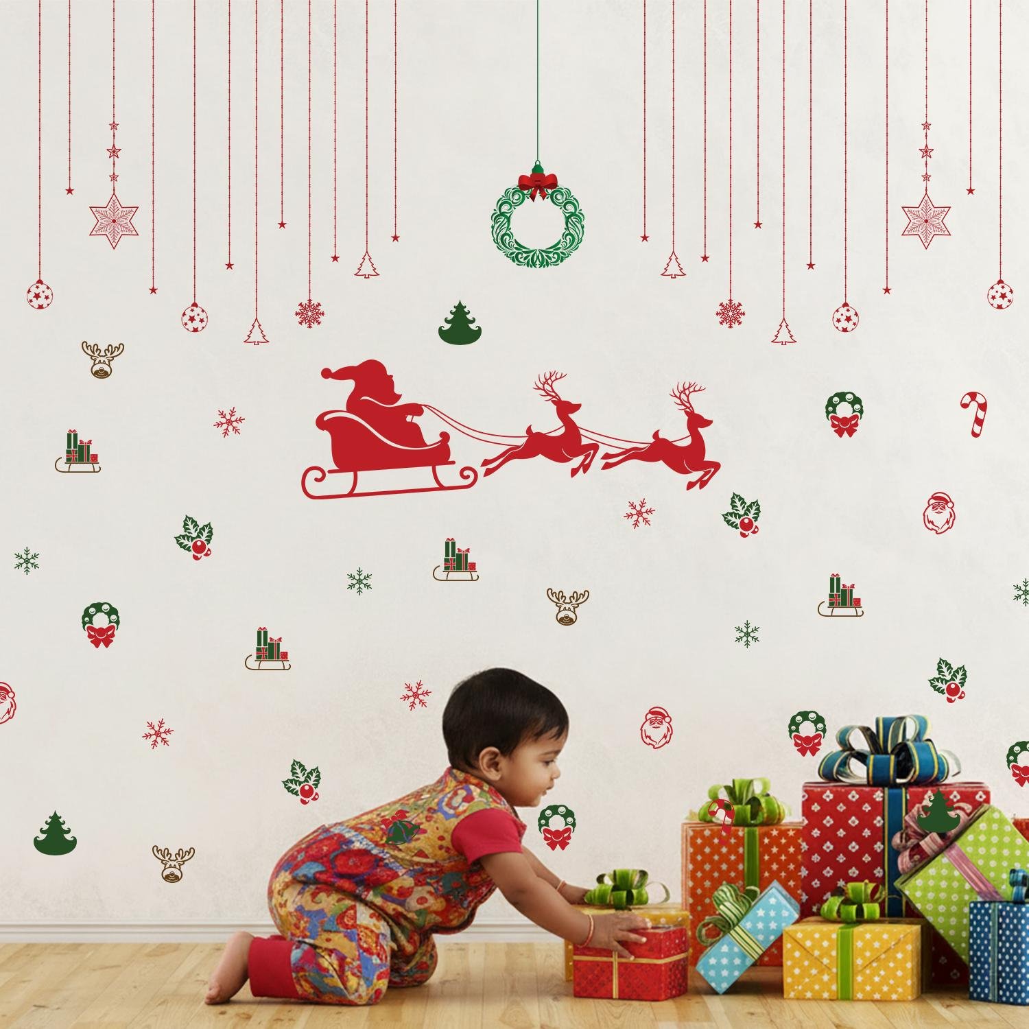 Christmas wall stickers featuring Santa sleigh, reindeer, wreaths, snowflakes, and festive hanging ornaments on a kids room wall