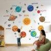 Kids room wall with colorful smiley solar system wall stickers including planets, sun, moon and space elements with child interacting