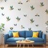 Minimalist botanical wall stickers featuring green leaves and yellow berry motifs arranged in a scattered pattern above a beige sofa in a modern living room.